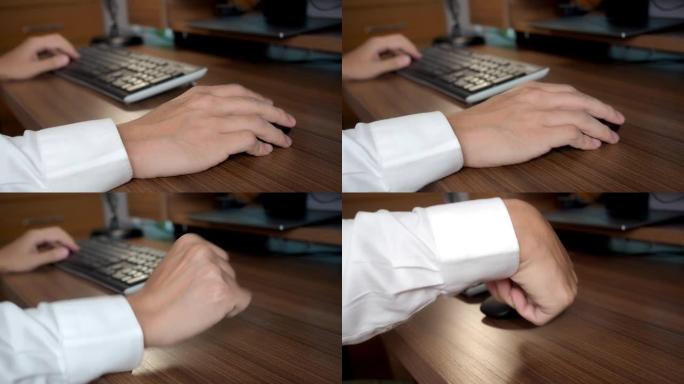 亚洲男子手腕的特写在家庭办公室使用台式电脑，他经历了严重的手腕疼痛，按摩他的手，并使手部运动受限。办