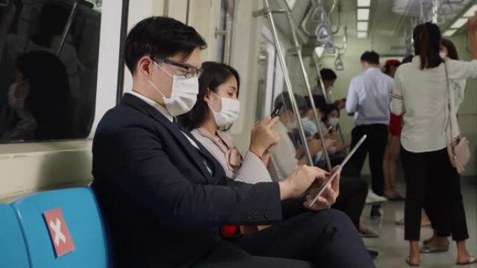 亚洲商人乘坐轻轨上班时戴着面具。预防公共场所的冠状病毒、细菌与人接触。商务人士在会议高峰时间和社交距