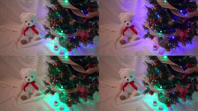 闪亮的圣诞树，在黑暗中有五颜六色的球和玩具。小白泰迪熊坐在圣诞树下，庆祝心情和童话概念