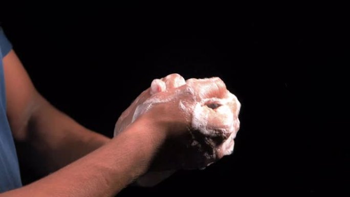 年轻人用肥皂洗手，温水隔离在黑色
