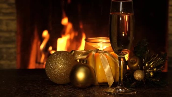 圣诞球，蜡烛，一杯香槟和在壁炉附近的桌子上落下的小火花