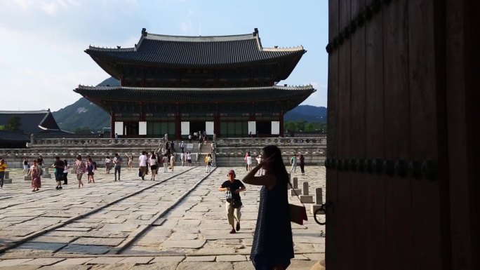 神社前有一盏红灯笼 一张桌子上放着很多食物 人们走在建筑物前的街道上