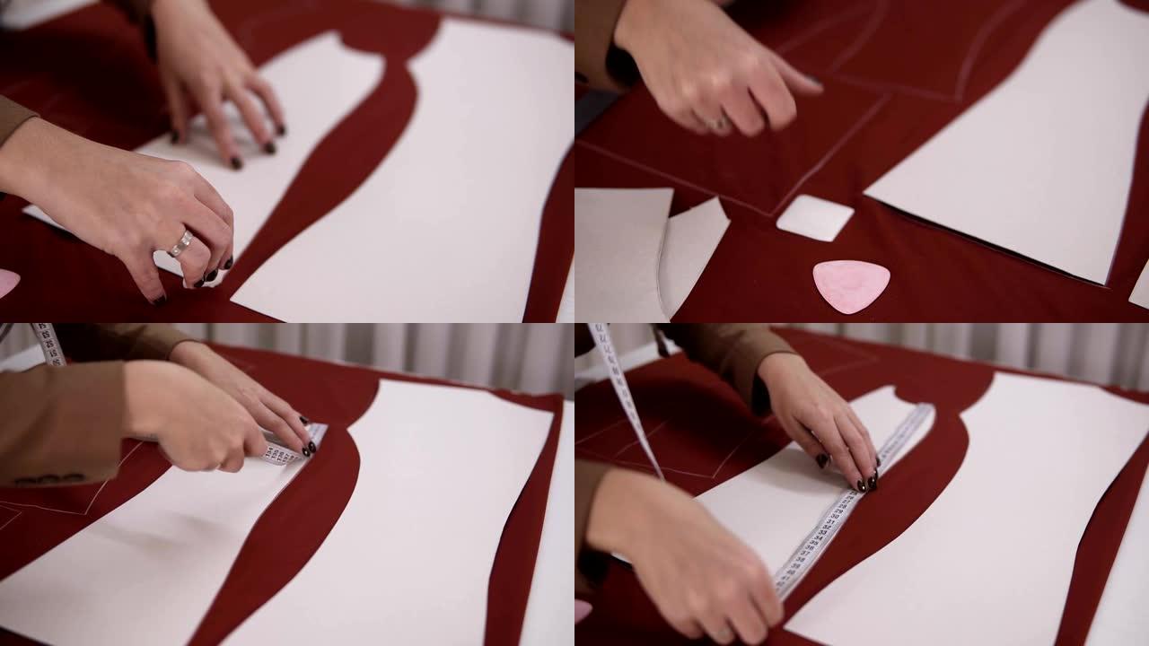 女裁缝在工作室里用红布在餐桌旁工作。熟练的女裁缝正在使用图案用肥皂或粉笔在红色织物上绘制素描线。完美