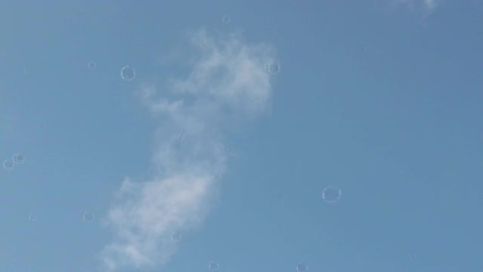 无忧无虑的肥皂泡在风的引导下在浅蓝色的天空中飞舞