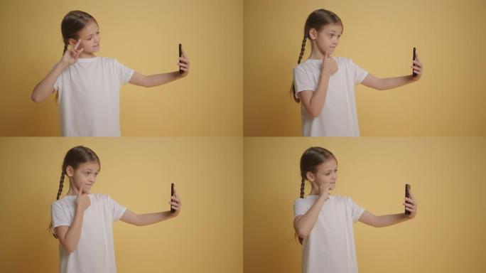 带辫子的女孩在黄色墙壁背景下在手机上自拍慢动作