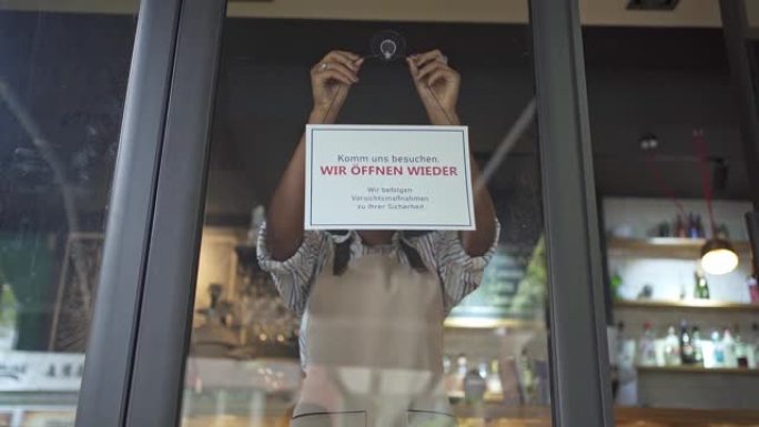 女服务员贴上有关她的咖啡店重新开业的信息标志
