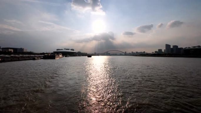 日落时分，在上海黄浦江上航行的船，大船后面的水尾迹与黄浦江沿线的上海城市地标有关。慢动作，4k镜头。