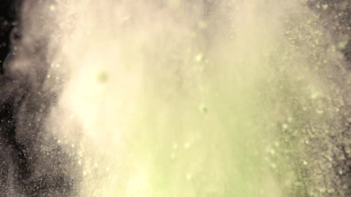 超慢动作爆炸彩色绿色粉末在黑暗孤立的背景。粉末团向上飞，与烟雾混合。