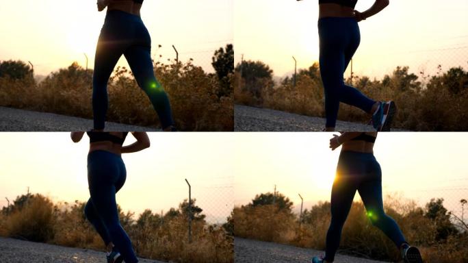 年轻健康女孩的脚在乡村道路上慢跑，背景是日出。室外跑步的苗条女性双腿。运动的女人在清晨锻炼。积极生活