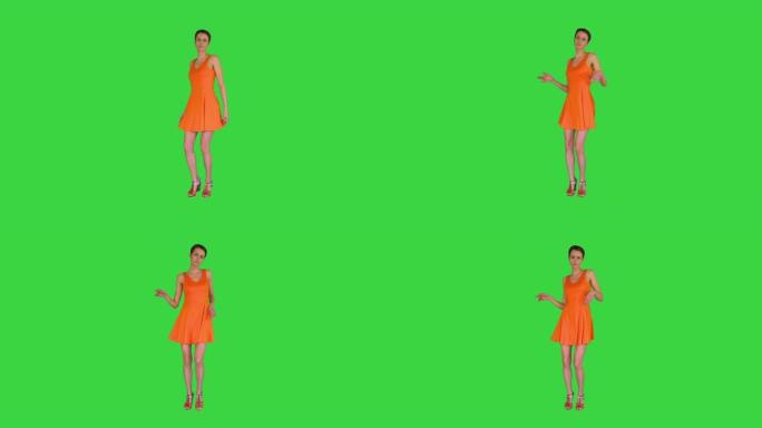 短发美女在绿色屏幕上穿着橙色太阳裙跳舞，色度键