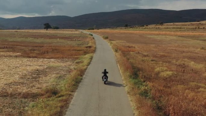 在乡村道路上驾驶摩托车的男子的无人机拍摄