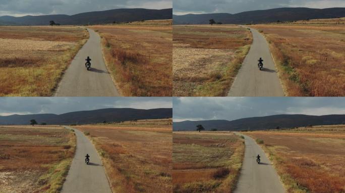 在乡村道路上驾驶摩托车的男子的无人机拍摄