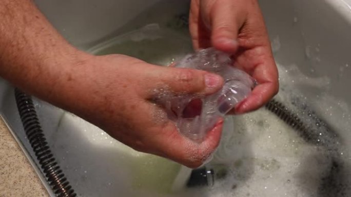 男性双手清洁CPAP鼻罩在水槽中。