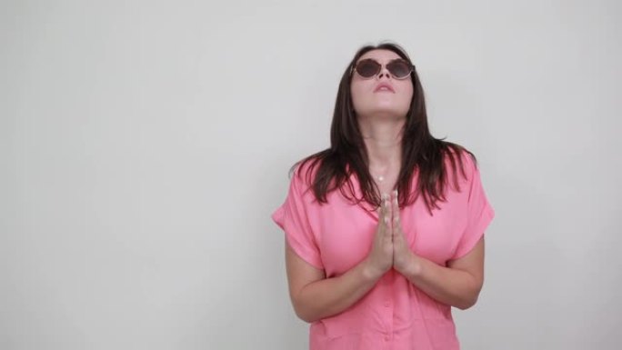 穿着粉红色衬衫和太阳镜的和平女人在一起祈祷