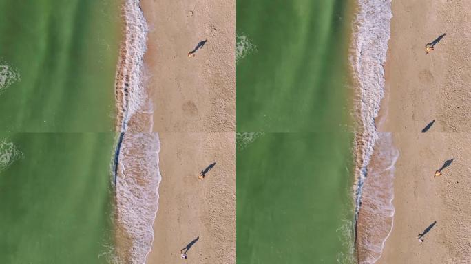 空中自上而下的镜头空着海岸，早上在沙滩上靠海水奔跑