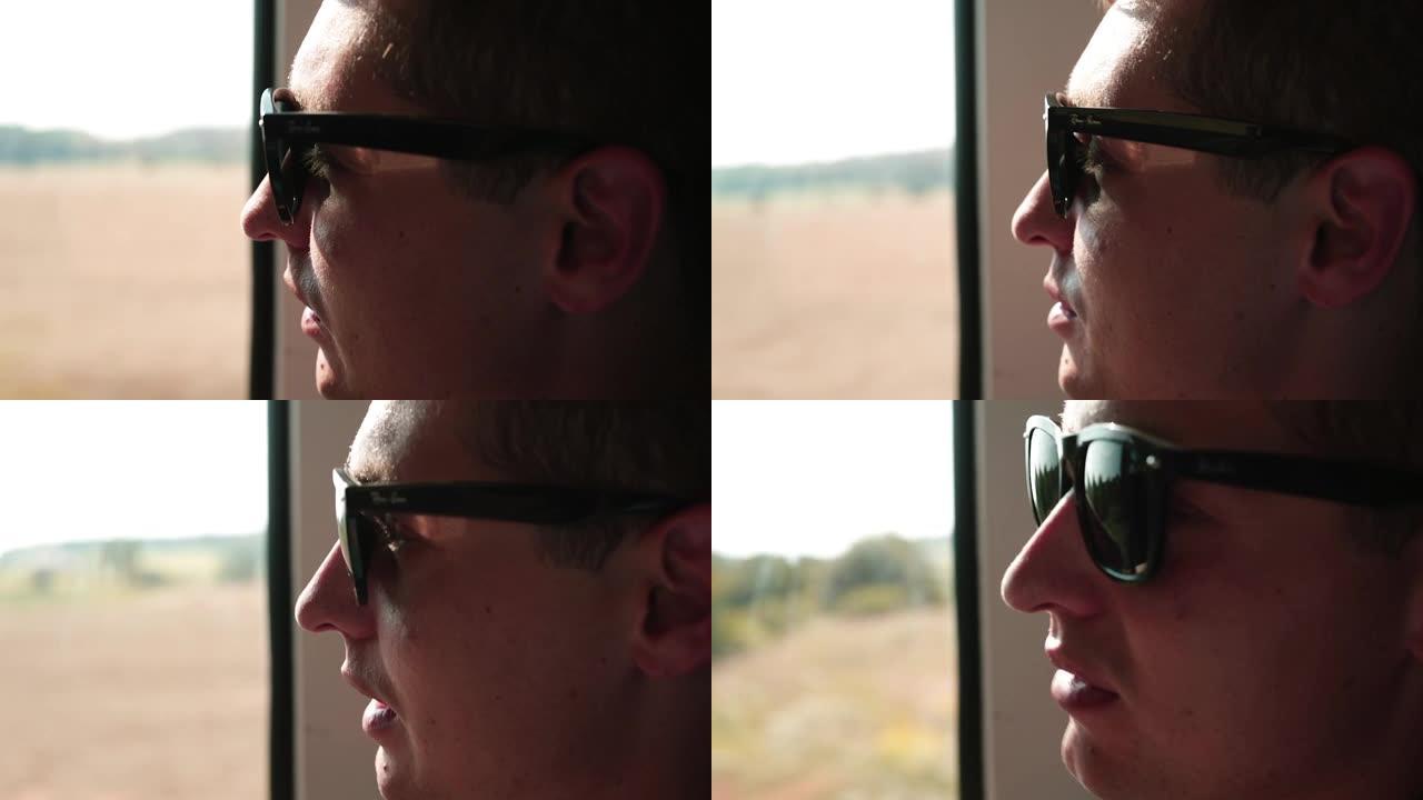 一个戴眼镜的人坐火车旅行。看着窗外，讲述一个故事。