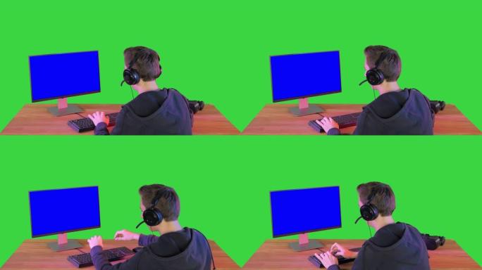 绿屏上有竞争力的年轻人在计算机上玩在线游戏的背面镜头，色键