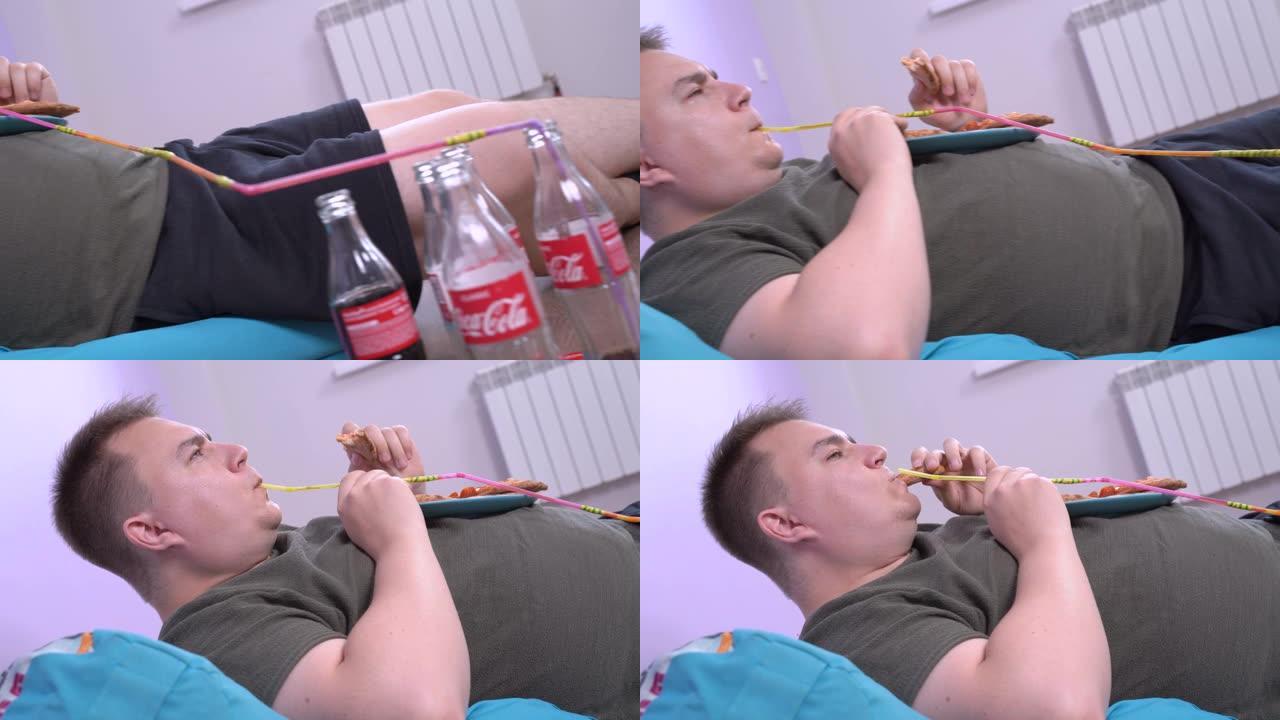 俄罗斯罗斯托夫2020年6月04日: 年轻又胖又懒的男人躺在沙发上，用长而手工制作的鸡尾酒吸管和许多