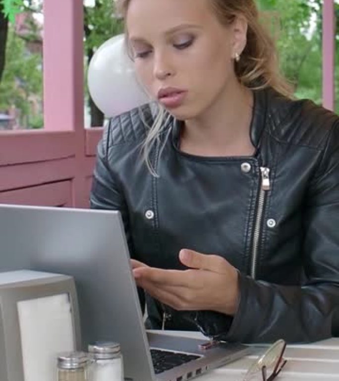 垂直视频-一个带着笔记本电脑的严肃女孩正在进行在线对话