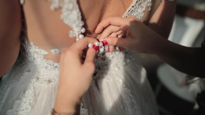 婚礼筹备期间的新娘和伴娘。伴娘帮助新娘打扮并为婚礼做准备。伴娘扣子婚纱
