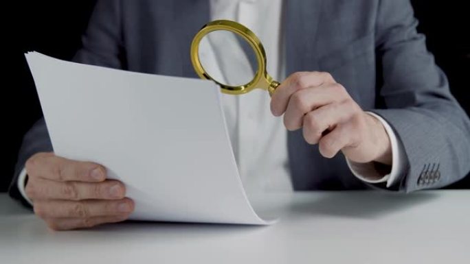 税务稽查员用放大镜检查财务文件。业务审计和数据分析