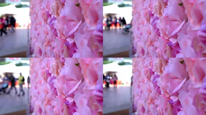 假日市场的粉红玫瑰墙。行人在模糊的背景上经过。