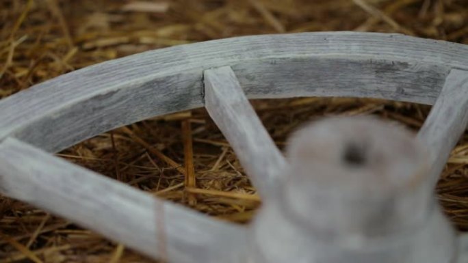 一个旧的白色木轮躺在干草上旋转