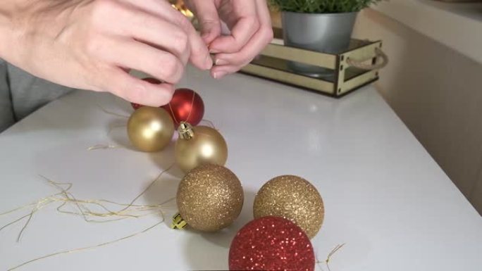 女人双手准备庆祝新年和圣诞节，她用绳子提供装饰性的彩色球，以便将其悬挂在杉木松树上