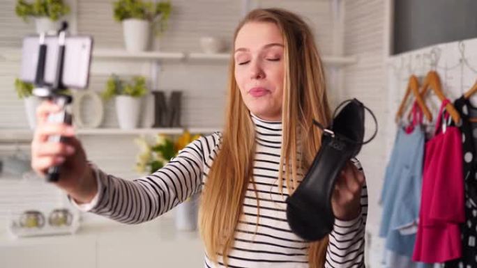 穿着高领毛衣的时尚博主女人在智能手机自拍相机上展示高跟鞋。造型师影响者女孩，时尚鞋类为频道拍摄vlo