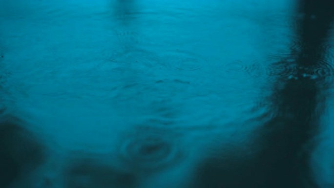 慢动作水滴落在地上的水面上，美丽的蓝色表面波抽象壁纸，地面上的圆圈图案，雨滴在潮湿的地板上落下和滴落