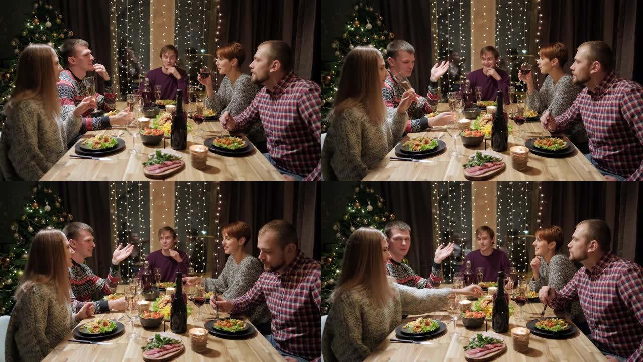 朋友假日聚会晚餐在家围桌吃饭。庆祝圣诞节。五个人吃饭，喝香槟，谈笑风声。