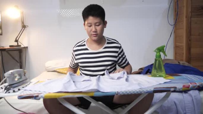 亚洲青春期男孩在夜间熨烫他的学生服，生活方式。