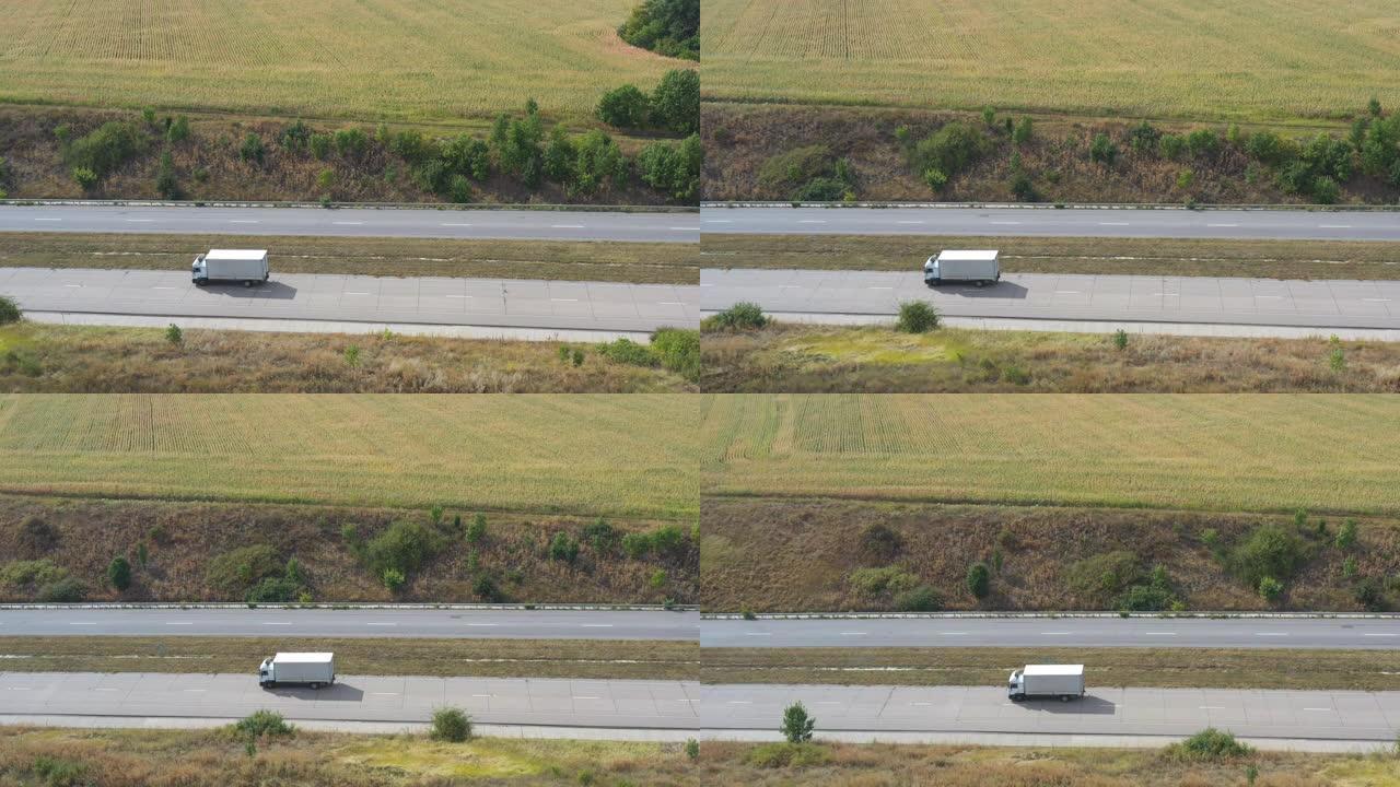 载货拖车在公路上行驶并运输货物的卡车的航拍。飞越送货卡车，沿着乡村的高速公路行驶，周围风景优美的自然