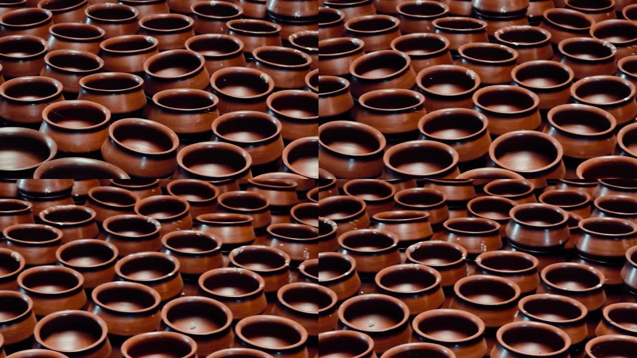 印度古吉拉特邦附近的传统陶器商店里一排未烘烤的陶土陶罐。俯视图大而短的古代花盆。生烤粘土陶器全框架拍
