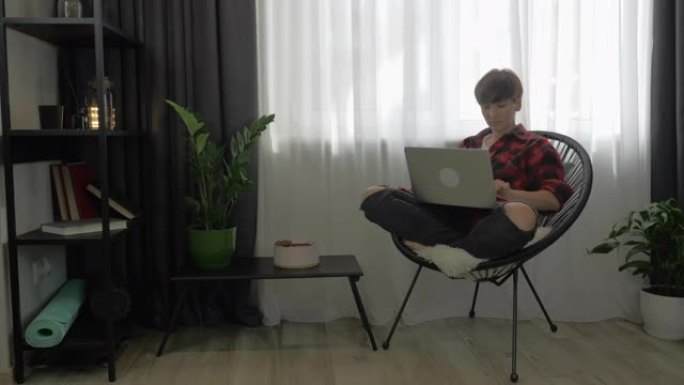 千禧一代的女工正在笔记本电脑上工作，在键盘上打字，在线观看新闻并在互联网上学习。女人在客厅里用笔记本