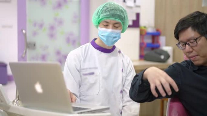 男性牙医使用笔记本电脑向他的亚洲男性患者展示牙齿的健康状况