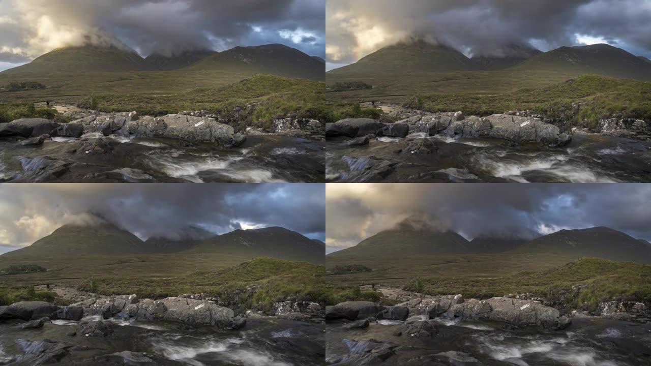 美丽的Sligachan瀑布位于苏格兰高地的斯凯岛上，Cuillin山脉被日落照亮，形成雾气上升到云
