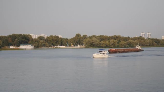 美丽的白色游艇漂浮在河上。小白船和旧生锈的驳船在河上航行。