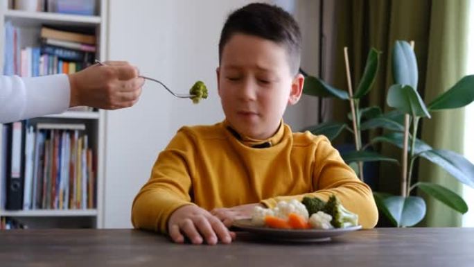 孩子对不得不吃蔬菜非常不满。他的盘子里有很多蔬菜。他讨厌蔬菜。