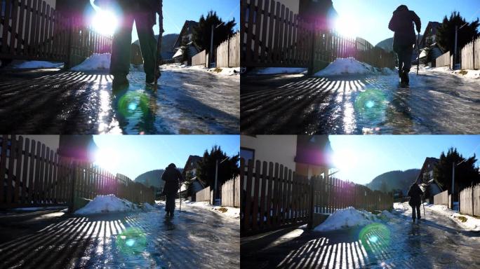 年轻的徒步旅行者在郊区的冰道上行走。晴天，无法识别的背着背包的家伙在旅途中走上冰冷的道路。寒假或假期