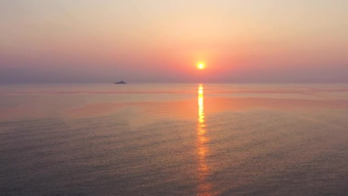 鸟瞰图，无人驾驶飞机在大洋上向后飞出五颜六色的早晨日出