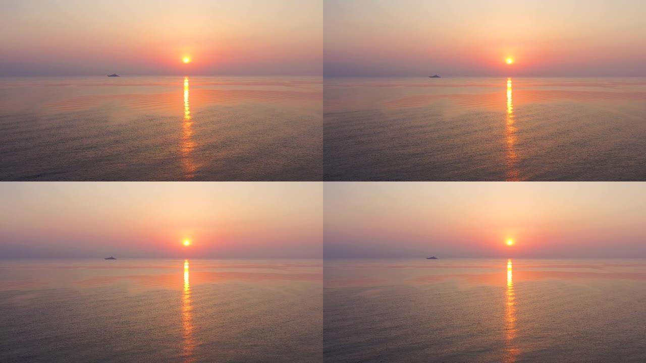 鸟瞰图，无人驾驶飞机在大洋上向后飞出五颜六色的早晨日出