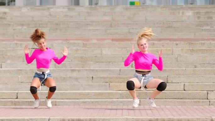 年轻开朗的女性在巨大的石头楼梯上在户外跳舞嘻哈舞蹈的二重奏。慢动作