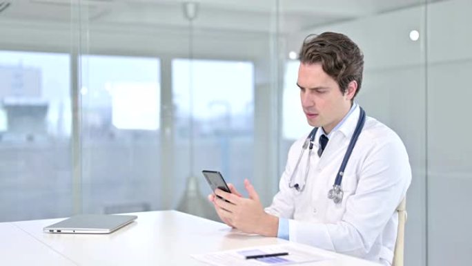 有吸引力的年轻男性医生在办公室使用智能手机