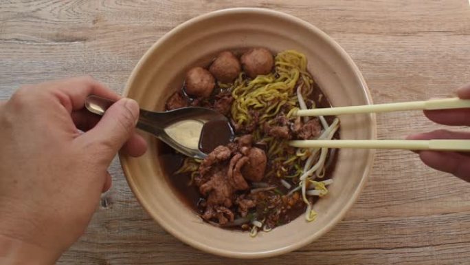 用勺子和筷子舀在棕色汤中的鸡蛋面