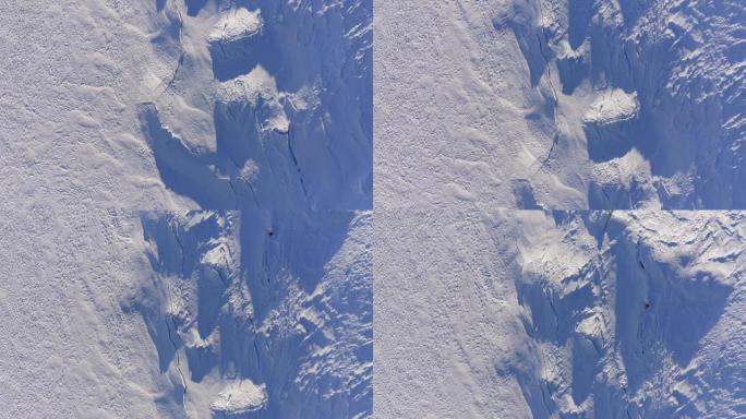 覆盖着积雪的冰川上方的俯视图裂缝和裂缝。温特兰户外设施。4k无人机头顶向前飞行建立射击。晴天积雪上的