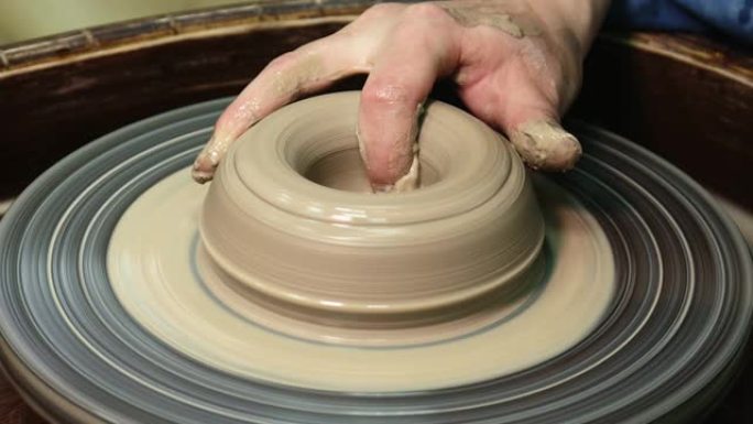 女人把手放在陶轮上。工匠艺术家塑造锅