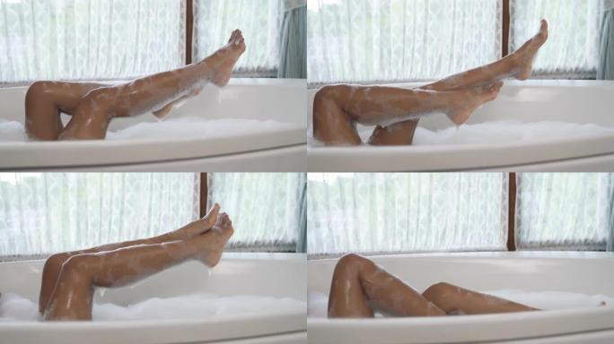 气泡浴中无法辨认的非洲妇女的腿的侧视图。纤细的双腿抬起，轻浮地躲在后面。