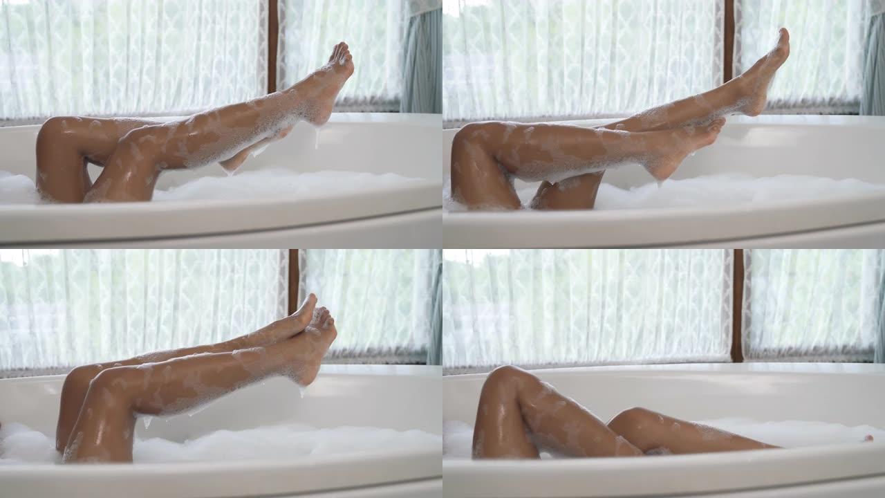 气泡浴中无法辨认的非洲妇女的腿的侧视图。纤细的双腿抬起，轻浮地躲在后面。
