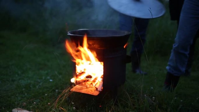 河岸上的大锅。火在它下面燃烧，柴火伸出。晚上，渔民要煮鱼汤